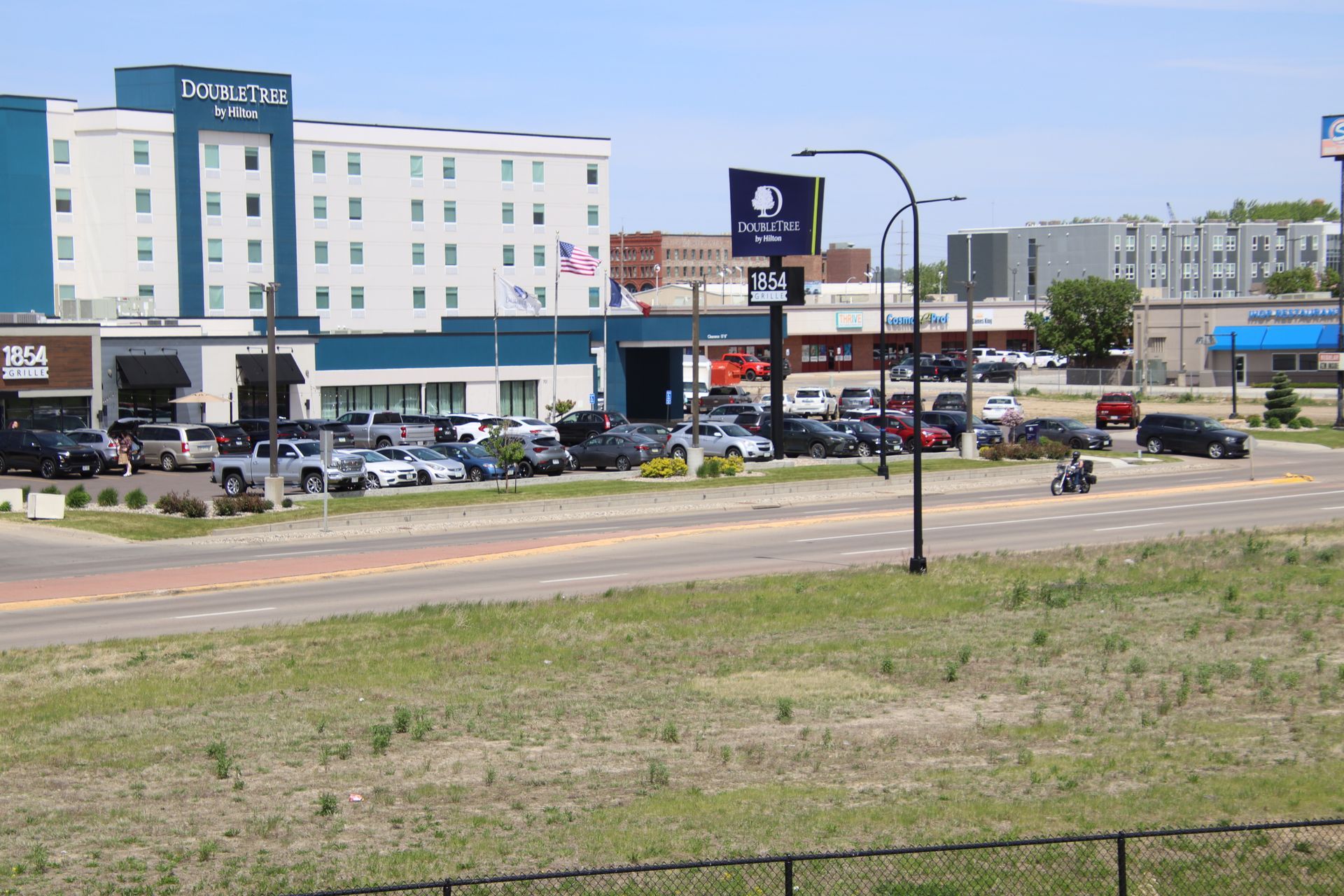Hotel and shopping area beside a busy road on a sunny day