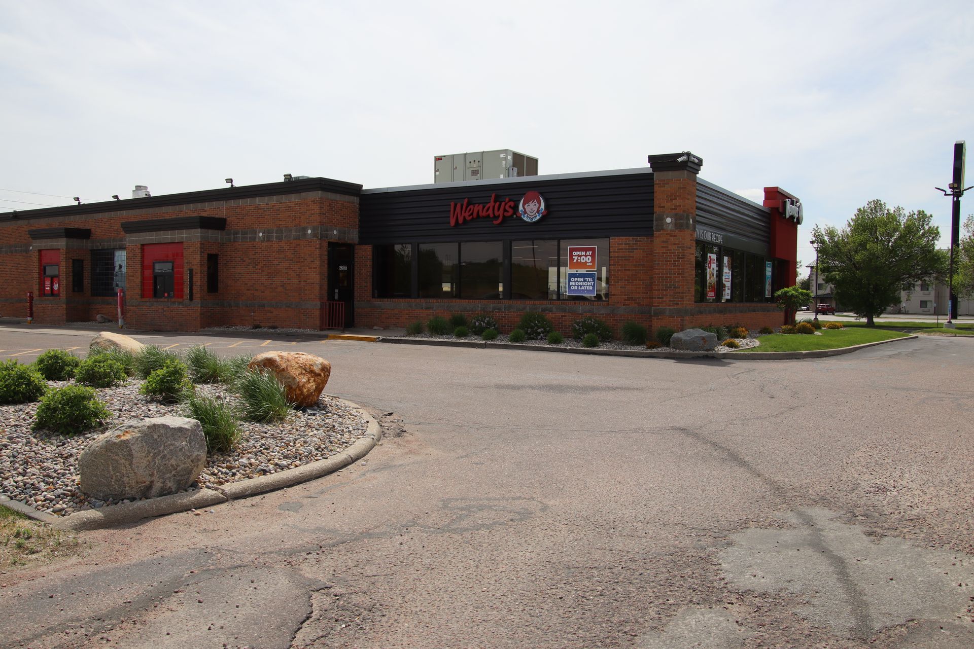 Brick Wendy’s restaurant with parking lot and landscaping under a cloudy sky