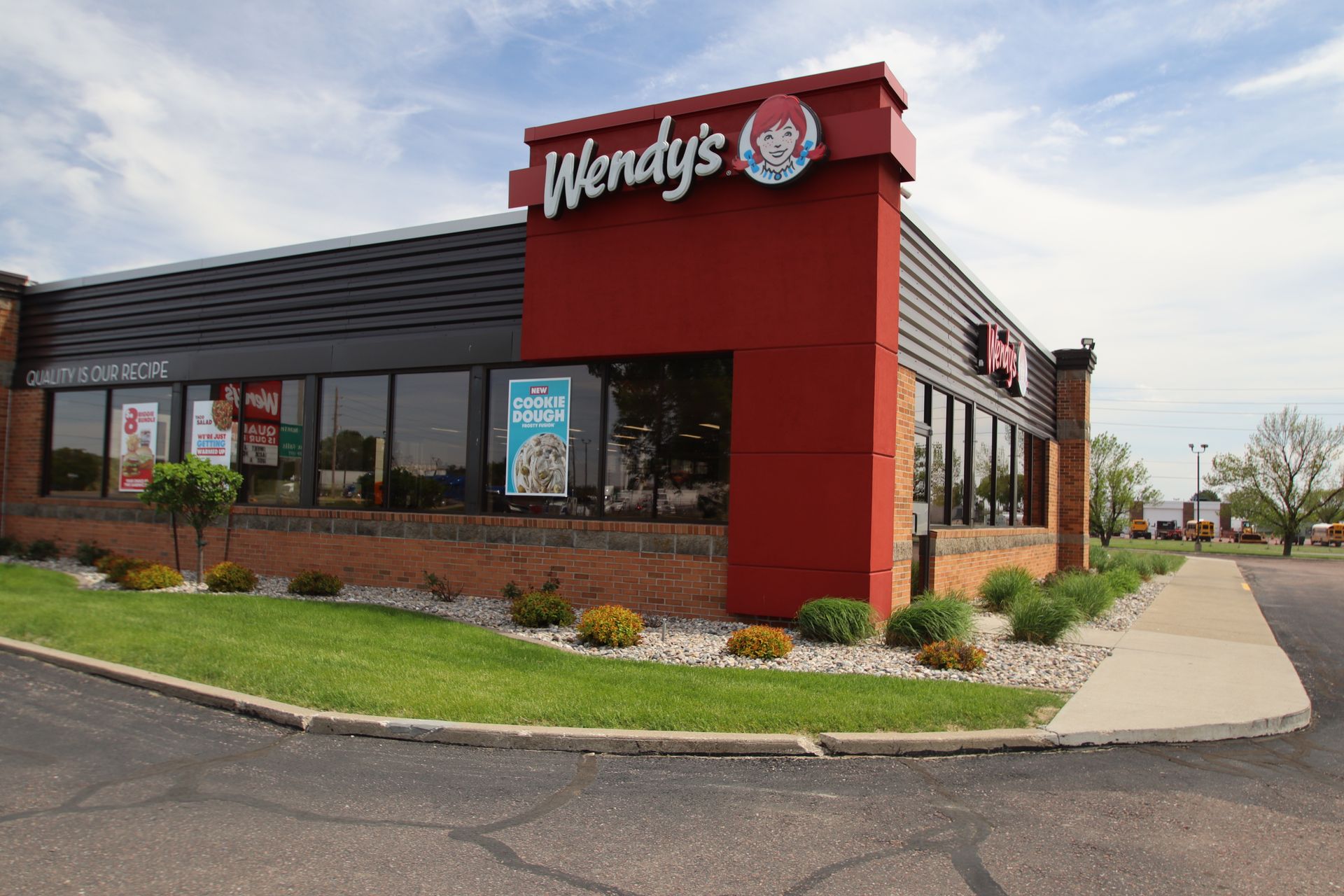 Wendy’s fast-food restaurant with red exterior, drive-thru window, and sidewalk corner view