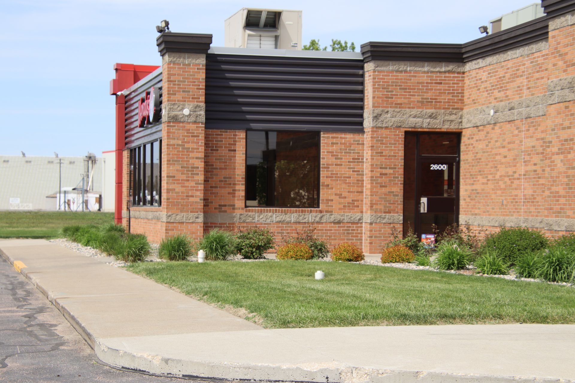 Brick building with large windows and a sidewalk on a quiet street