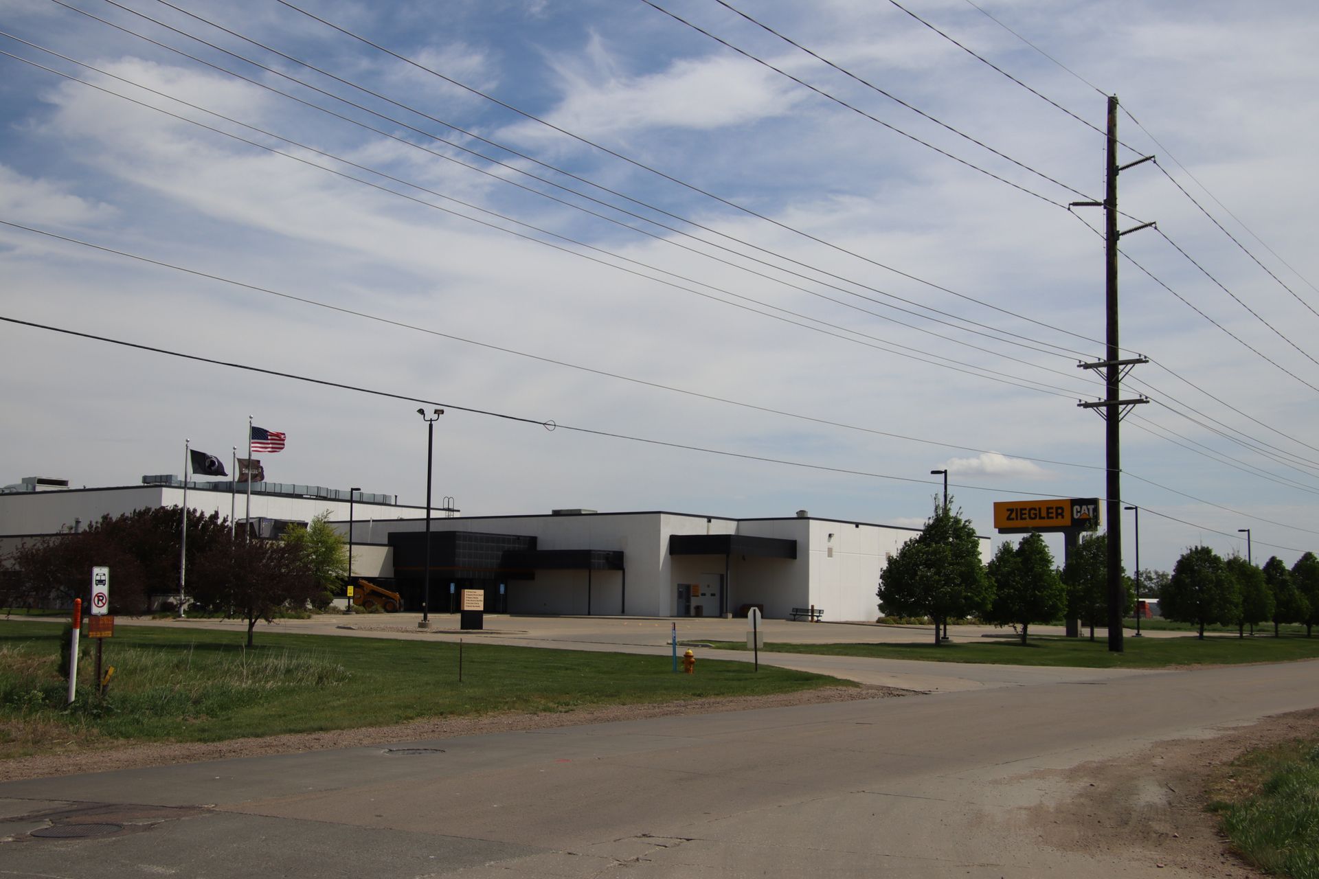 Rural roadside building with American flag, utility poles, and cloudy sky.