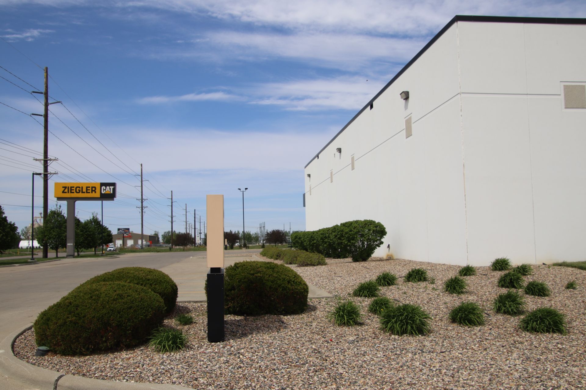 White building beside a roadside sign and desert landscaping under a blue sky
