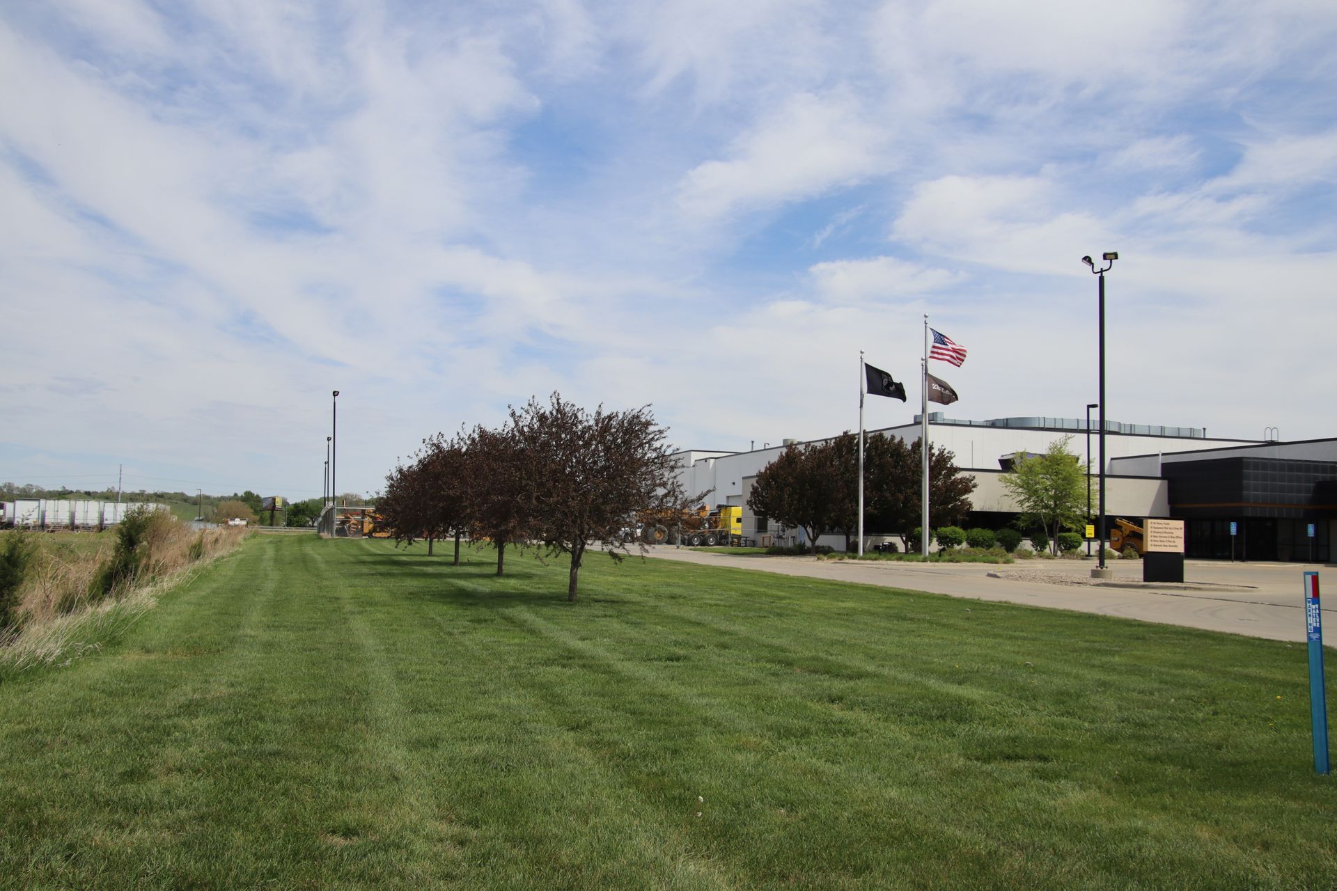 Grassy field beside a building with flags flying under a cloudy sky