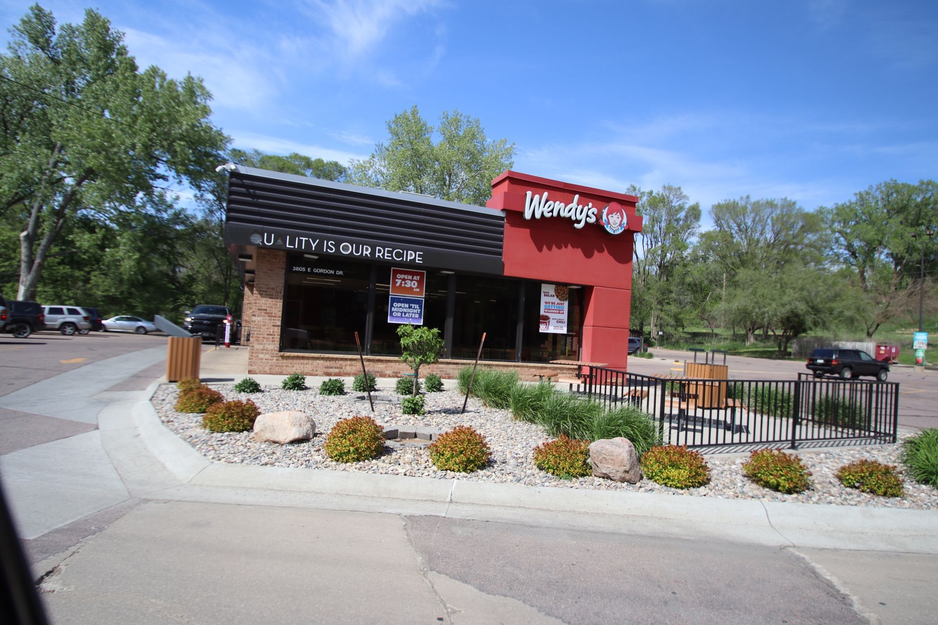 Wendy’s restaurant exterior with red sign, outdoor seating, and landscaped drive-thru entrance