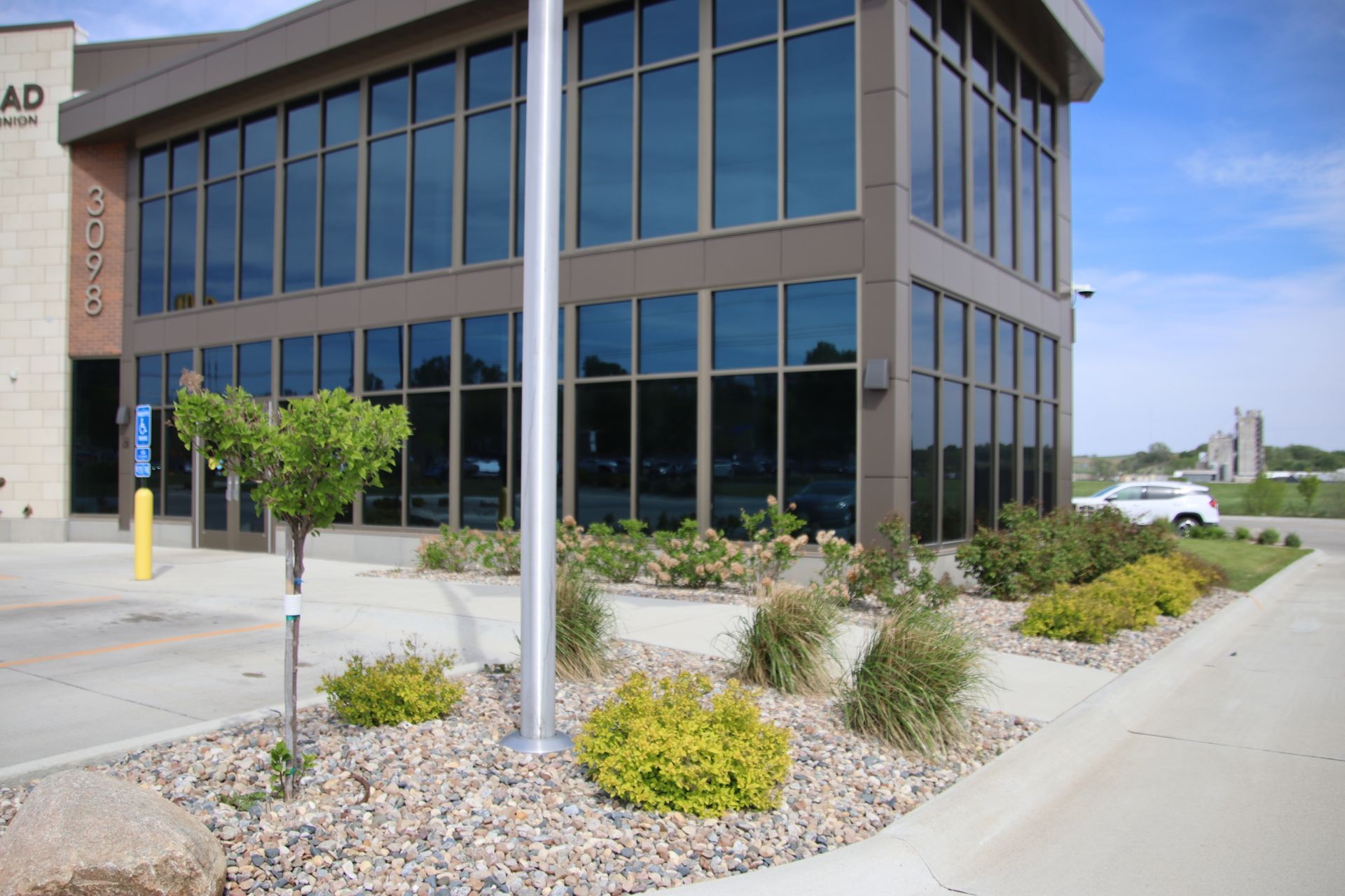 Modern office building with large windows and desert landscaping by a sidewalk