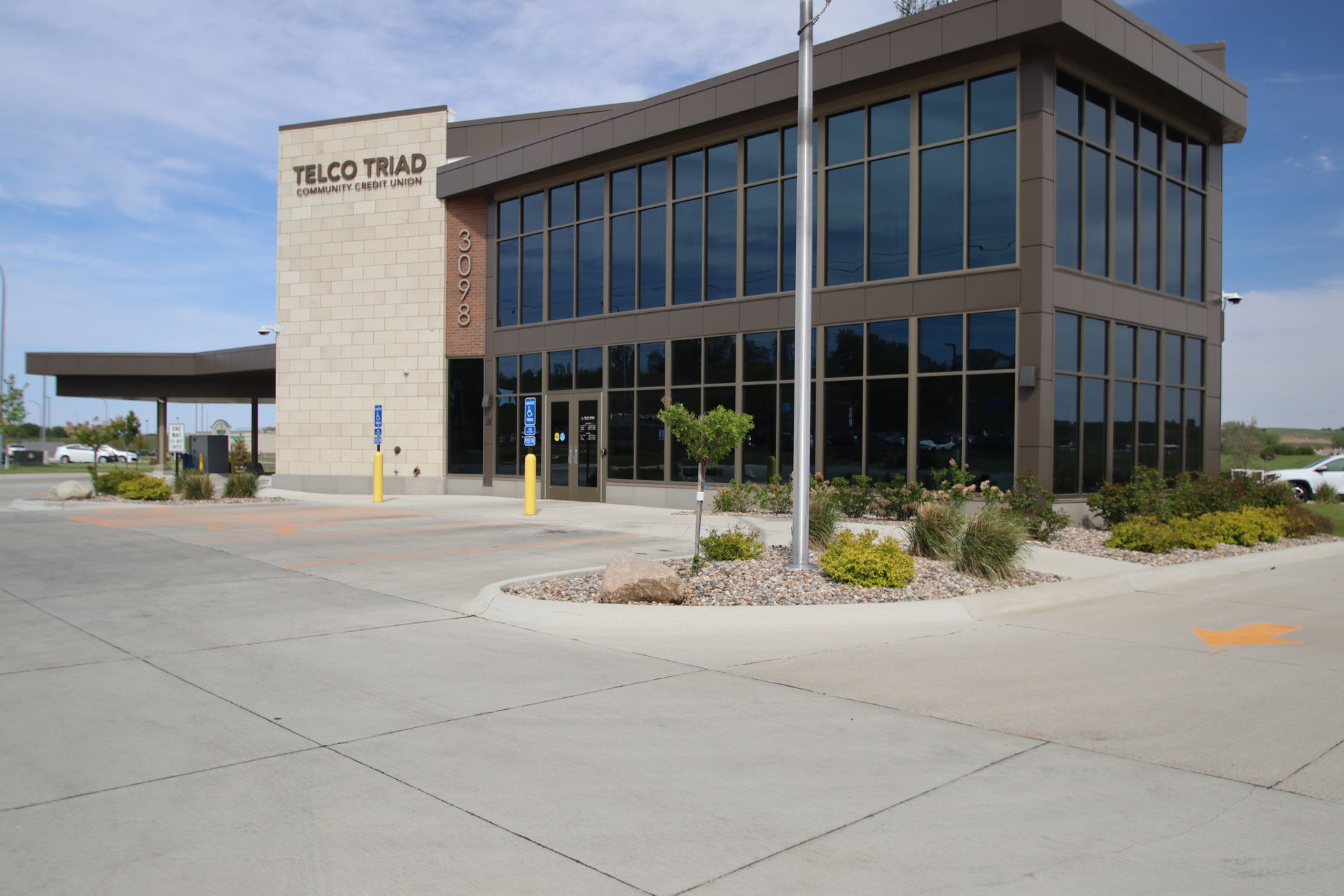 Modern office building with large windows and a parking lot in front