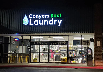 Conyers Best Laundry storefront at night with illuminated signs and glass windows