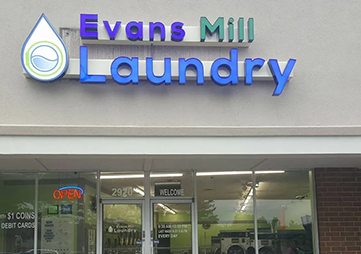 Evans Mill Laundry storefront sign above glass entrance on a gray building