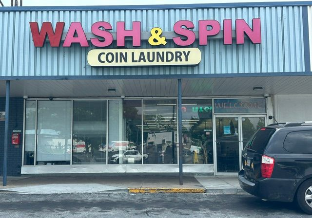 Wash & Spin Coin Laundry storefront with glass windows and a parked SUV outside