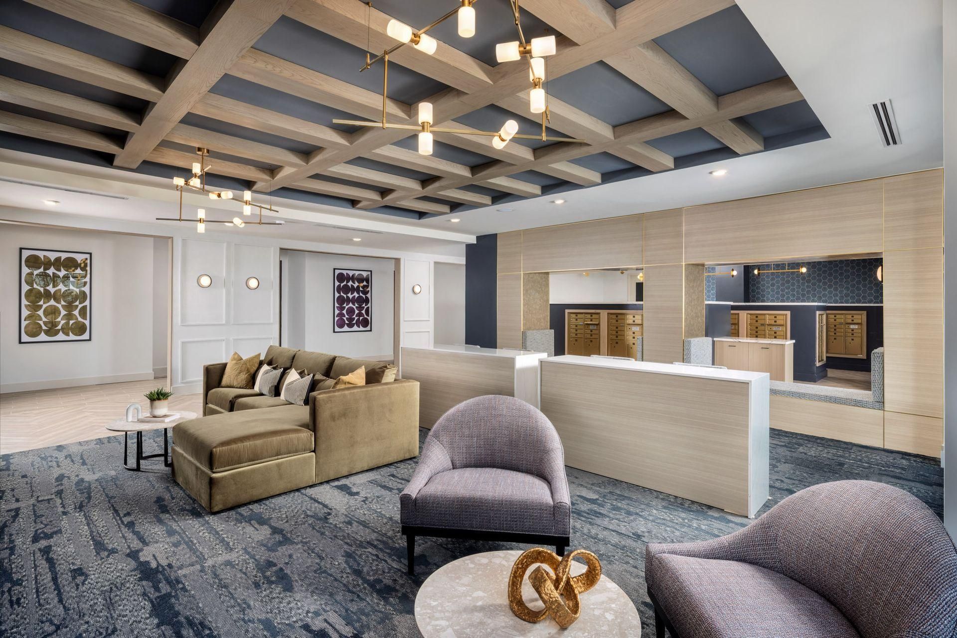Modern lounge with sofas, armchairs, patterned rug, and open ceiling lights in a bright office lobby