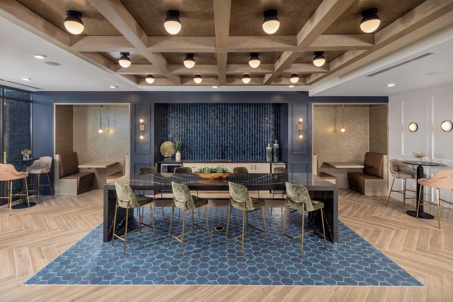 Modern dining room with blue patterned rug, long table, warm wood ceiling, and pendant lights.