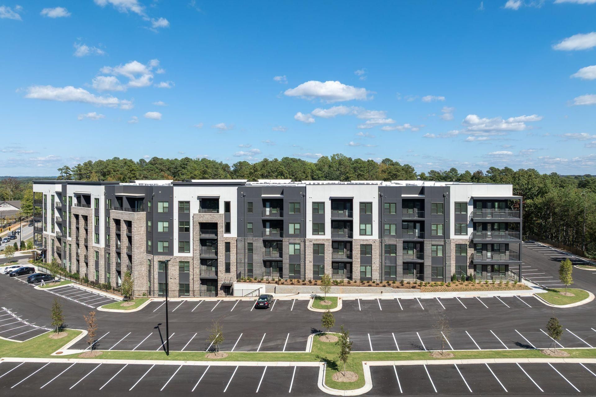 Modern three-story apartment building with parking lot under a blue sky