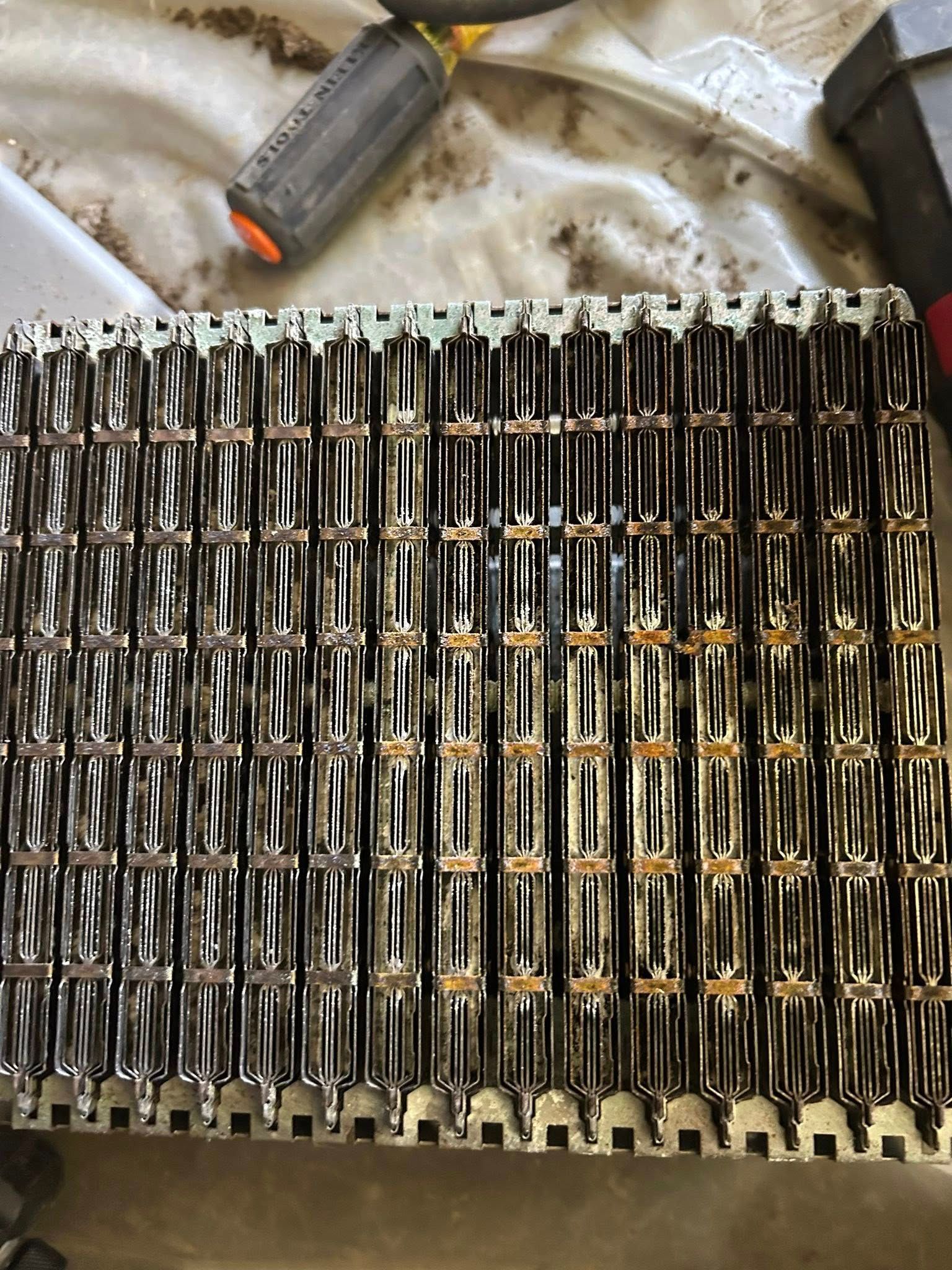 A close-up view of a metal furnace heat exchanger with a series of vertical, ribbed combustion channels.