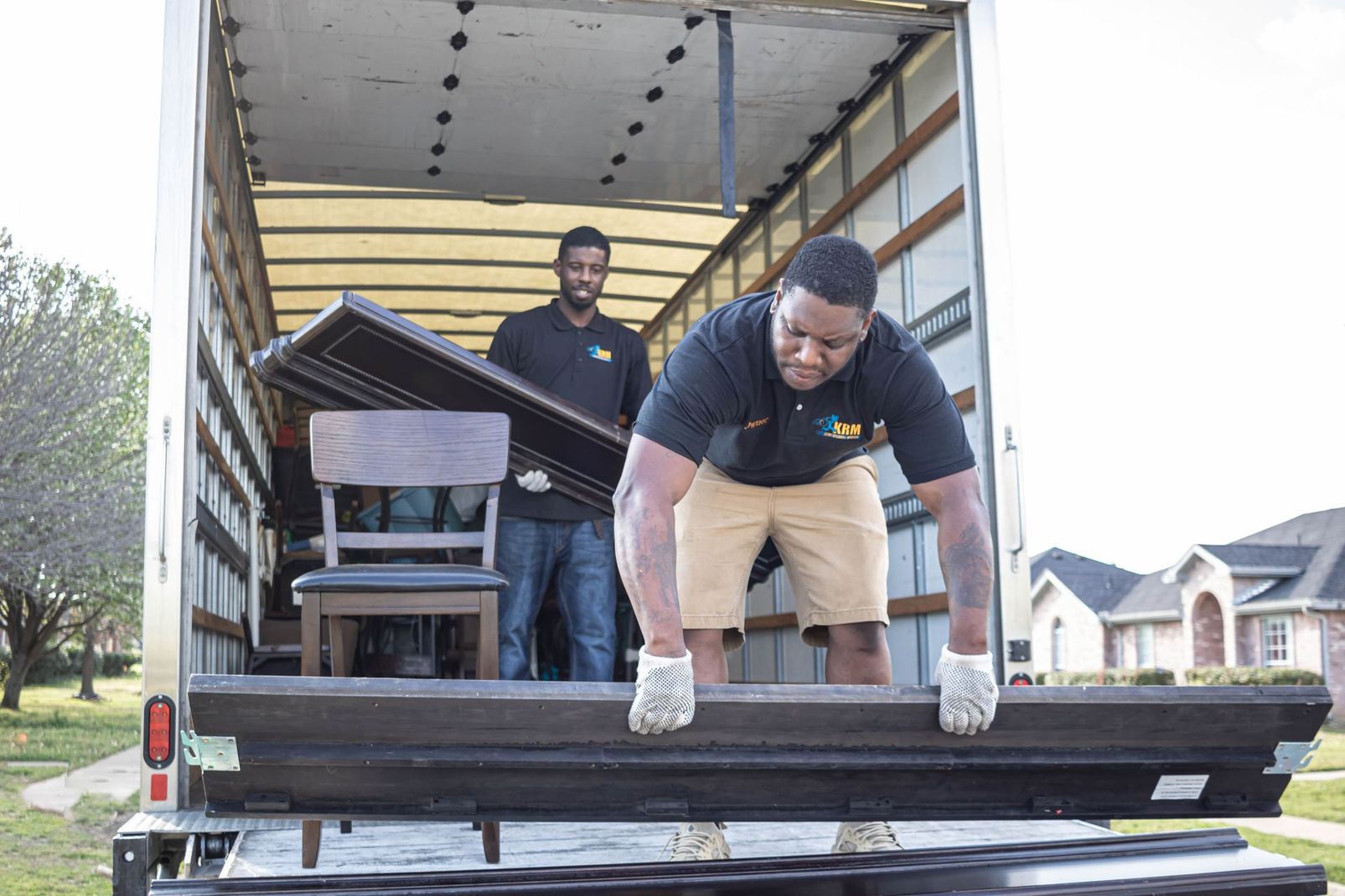 Two men loading large wooden panels onto a truck in a residential driveway