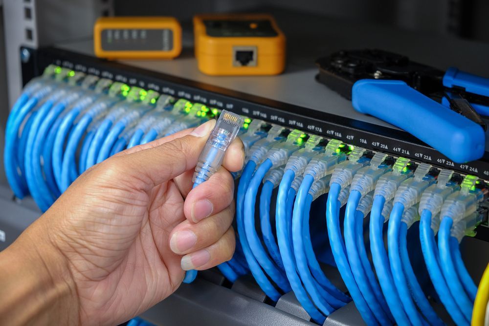 A Person is Holding a Wire in Their Hand in Front of a Bunch of Wires — Frontier Connect in Newtown, QLD