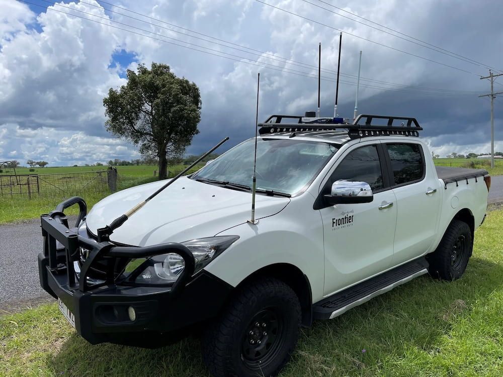 A White Truck With a Roof Rack is Parked in a Grassy Field — Frontier Connect in Newtown, QLD