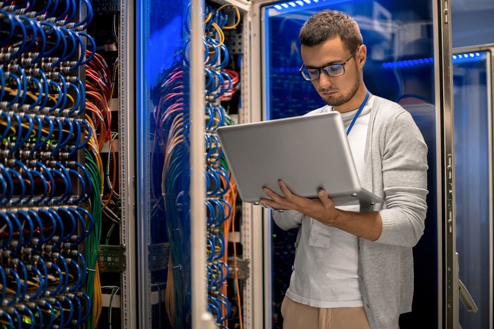 A Man is Holding a Laptop in a Server Room — Frontier Connect in Warwick, QLD