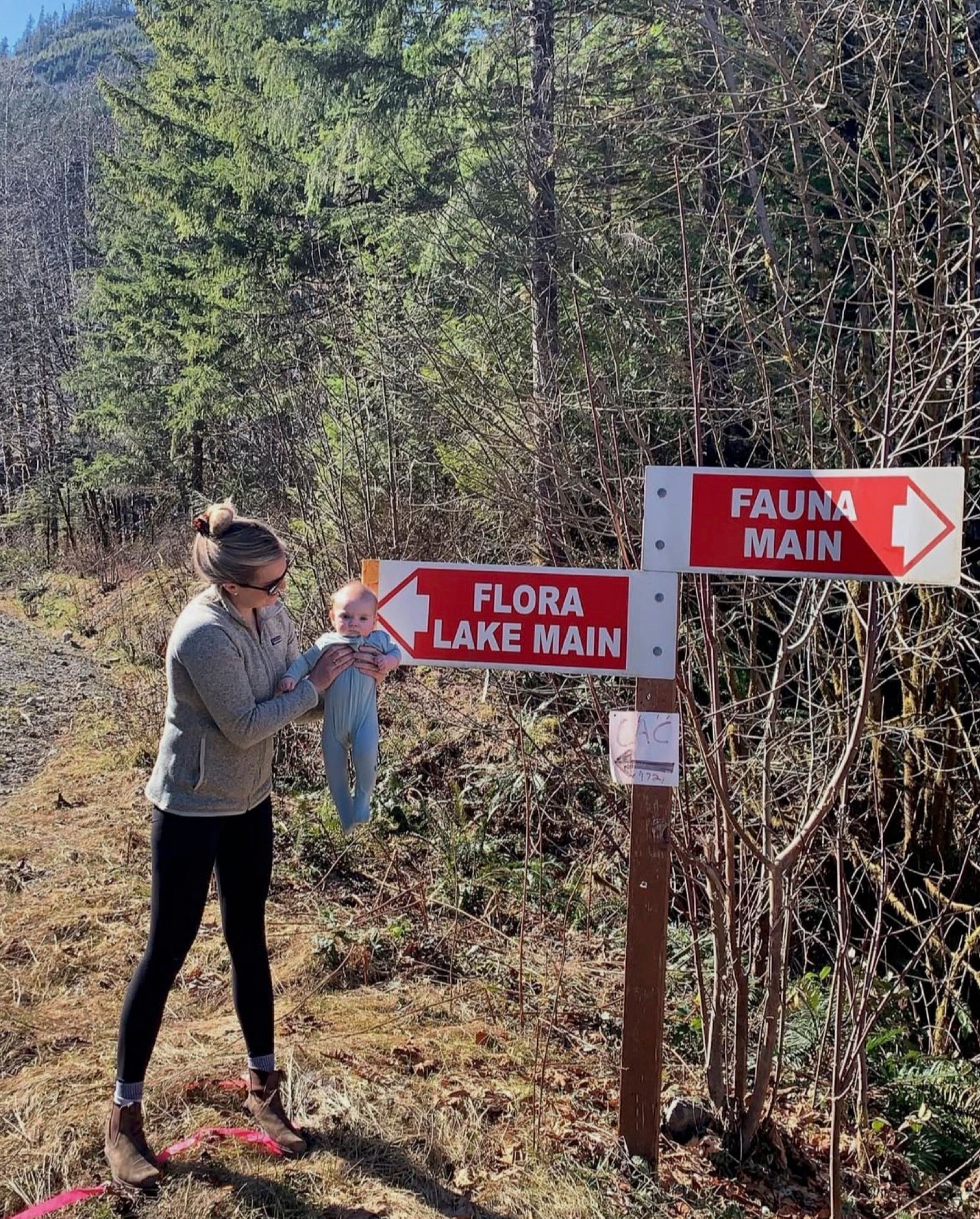 A woman is standing next to a sign that says flora lake main.