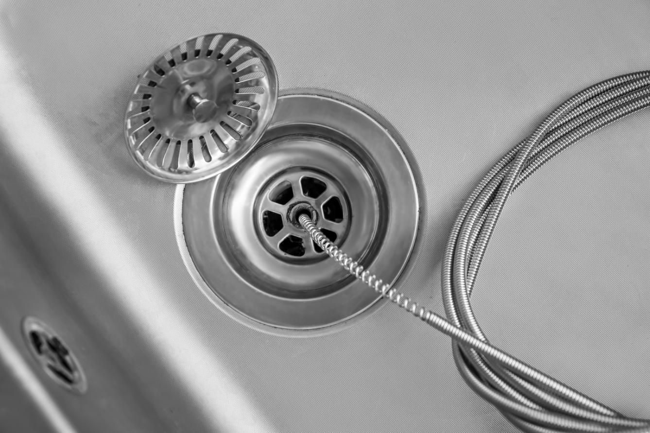 Chrome sink drain with stopper and metal cable looped beside it
