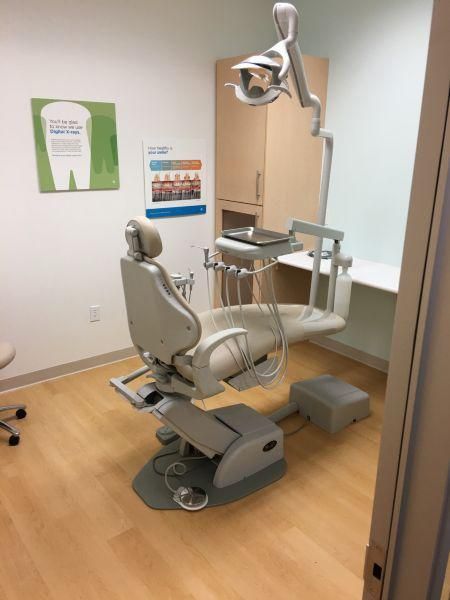 Dental exam room with a reclining chair, overhead light, and cabinet in a clean clinic setting