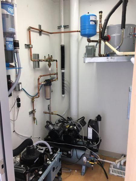 Basement utility room with pipes, pumps, and a blue pressure tank in front of a white water heater