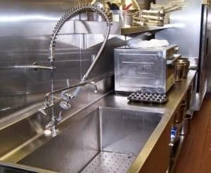 Stainless steel commercial kitchen sink with spring faucet and dish rack on a counter