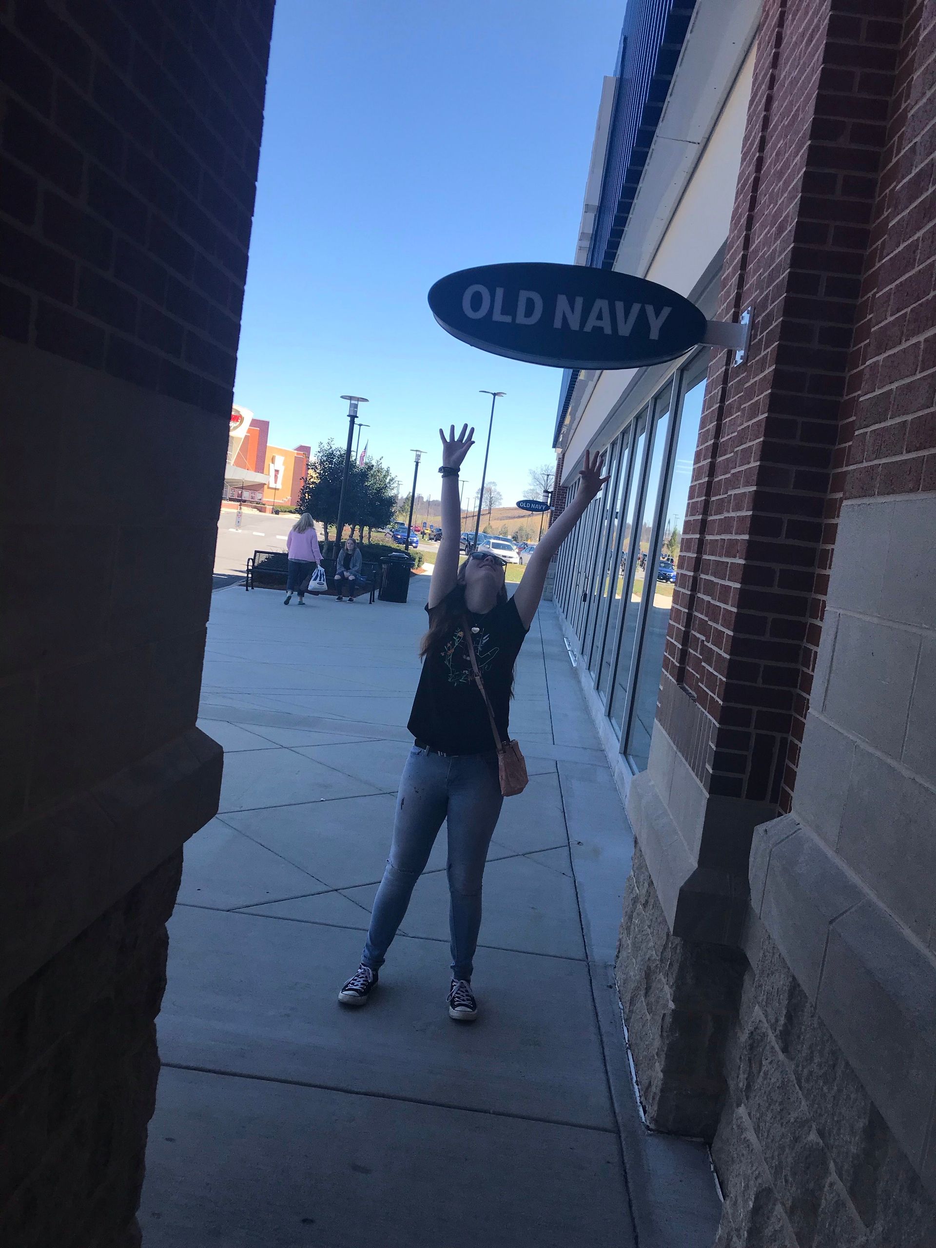 Person standing on a sidewalk outside the Old Navy store entrance.
