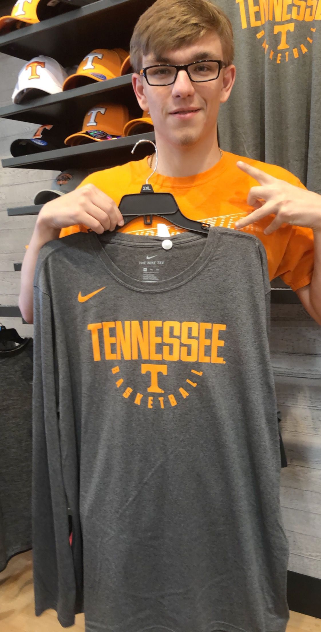 Person holding a gray Tennessee Nike T-shirt in a sports store