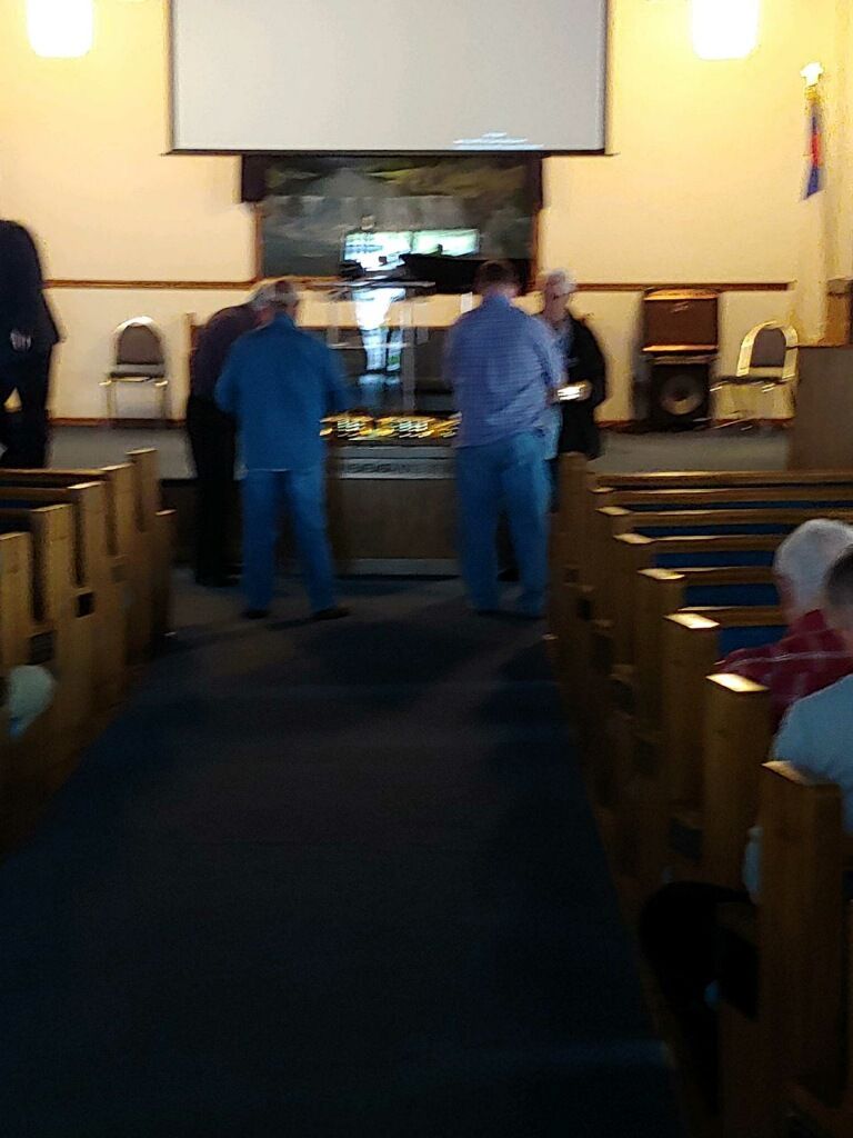 Two people standing at the front of a church sanctuary with pews and a pulpit visible