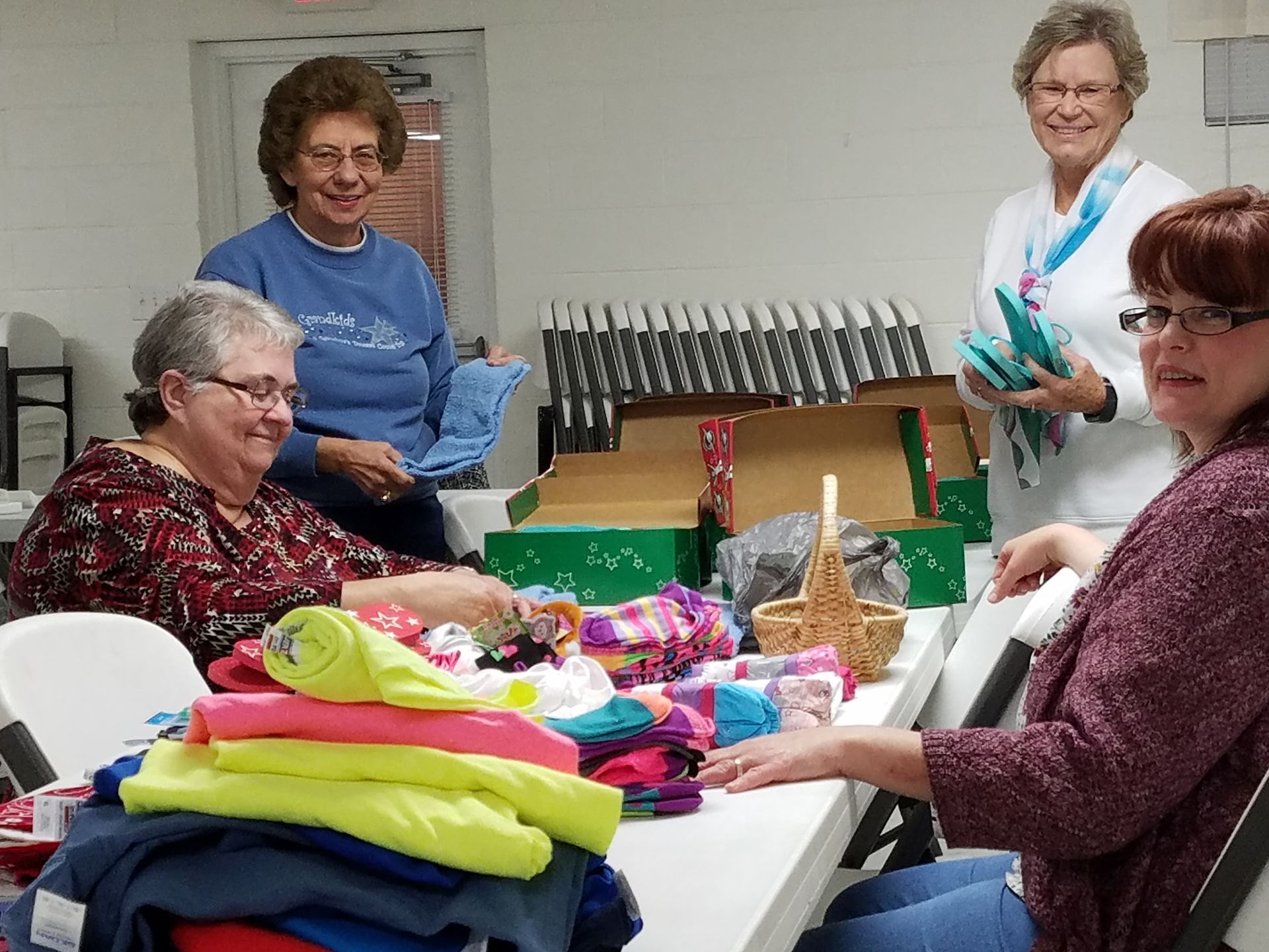 People gathered around a table sorting colorful folded items in a bright room