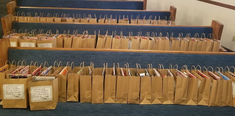 Rows of brown paper bags with tags, each holding paired metal hooks, arranged on shelves in a workshop or store