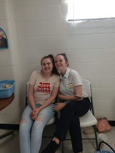 Two people sitting close together on a bench in a bright room, smiling at the camera.