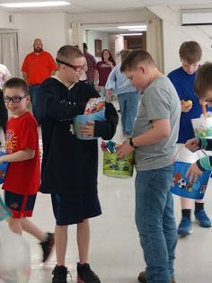 Children standing in a hallway, looking at items and chatting during a school activity