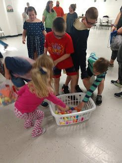 Children gathering toys from a basket in a bright room