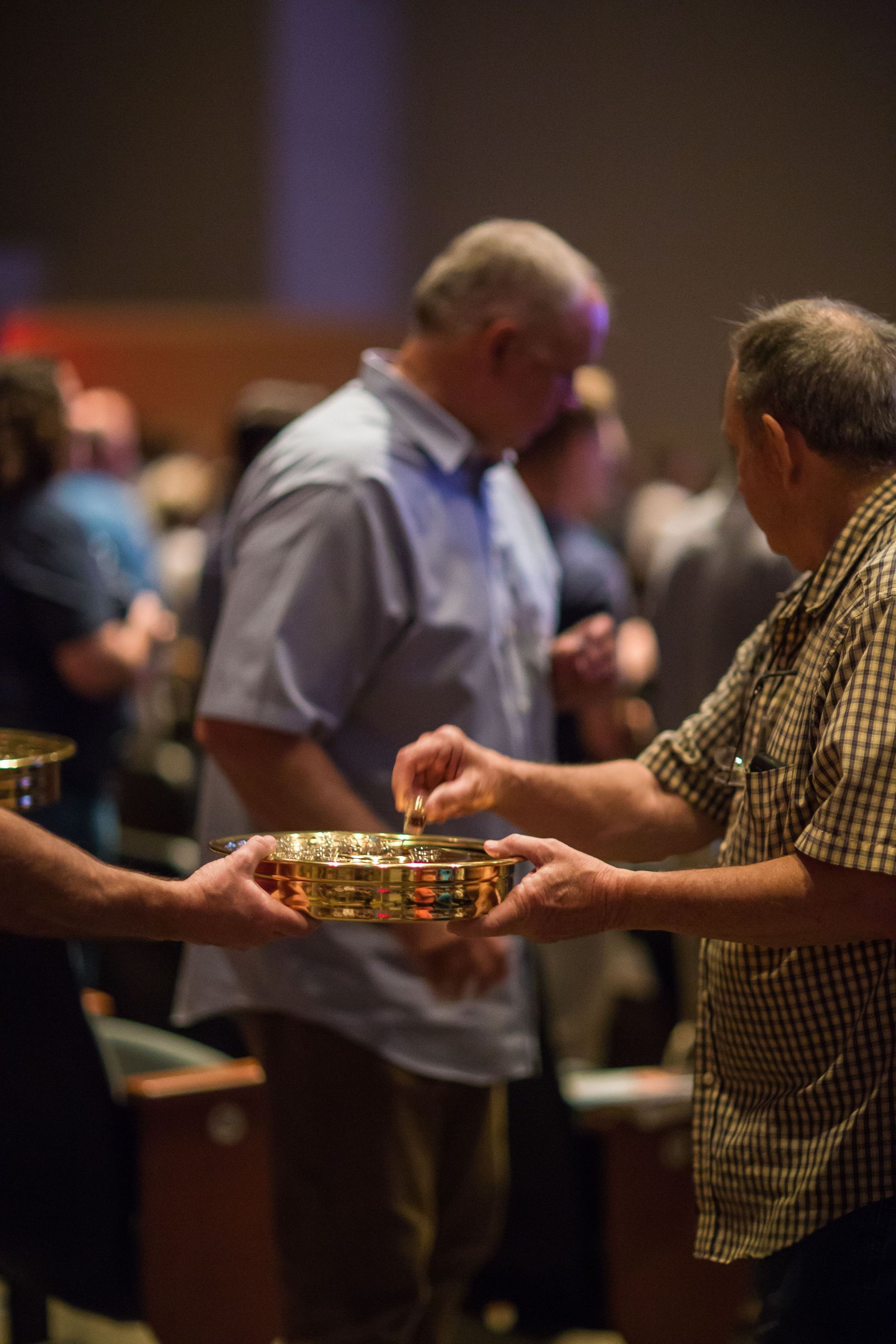 People passing gold offering plates in a church or community gathering