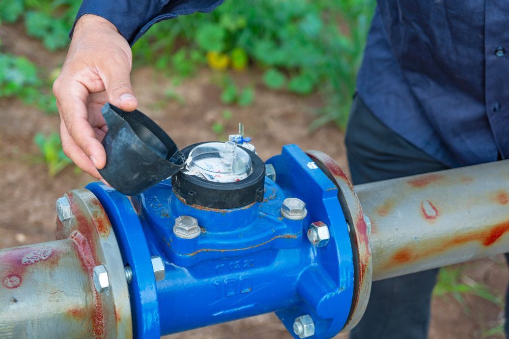 Person Opening a Blue Water Meter in an Outdoor Setting — Forcequip In Mackay, QLD