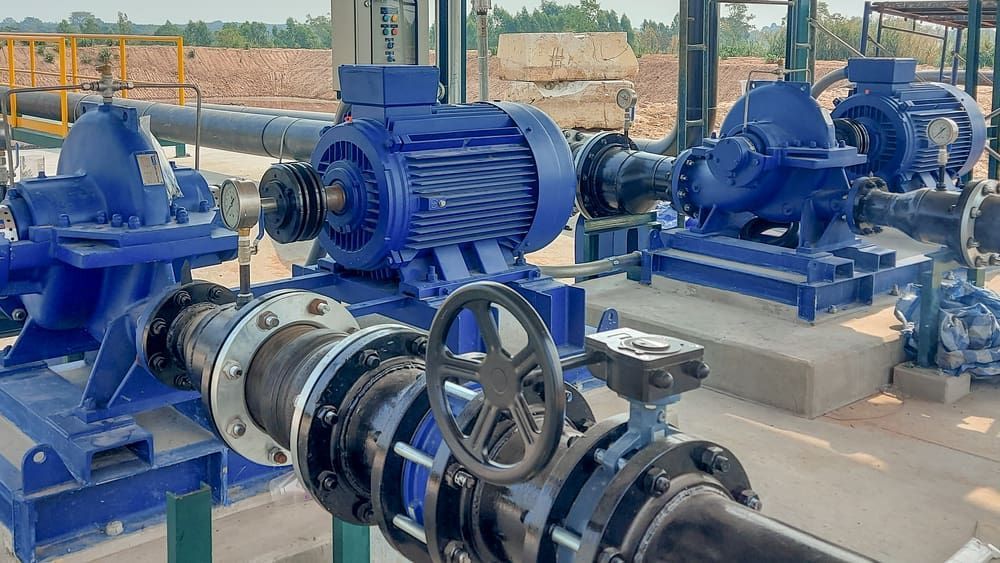 Blue industrial pumps and electric motors mounted on a concrete pad in an outdoor facility - Forcequip Glanmire QLD