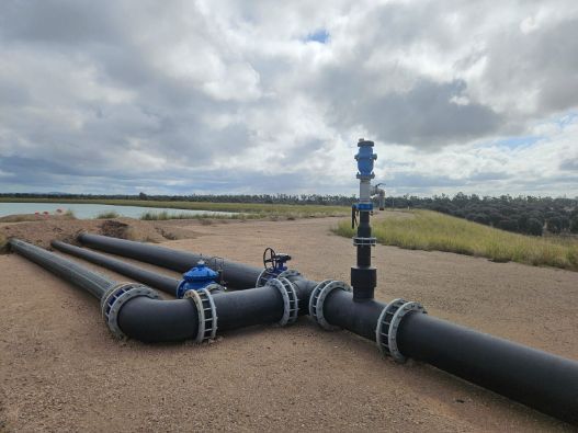 Black Pipes With Valves on Sandy Ground Under a Cloudy Sky — Forcequip Hire In Glanmire, QLD