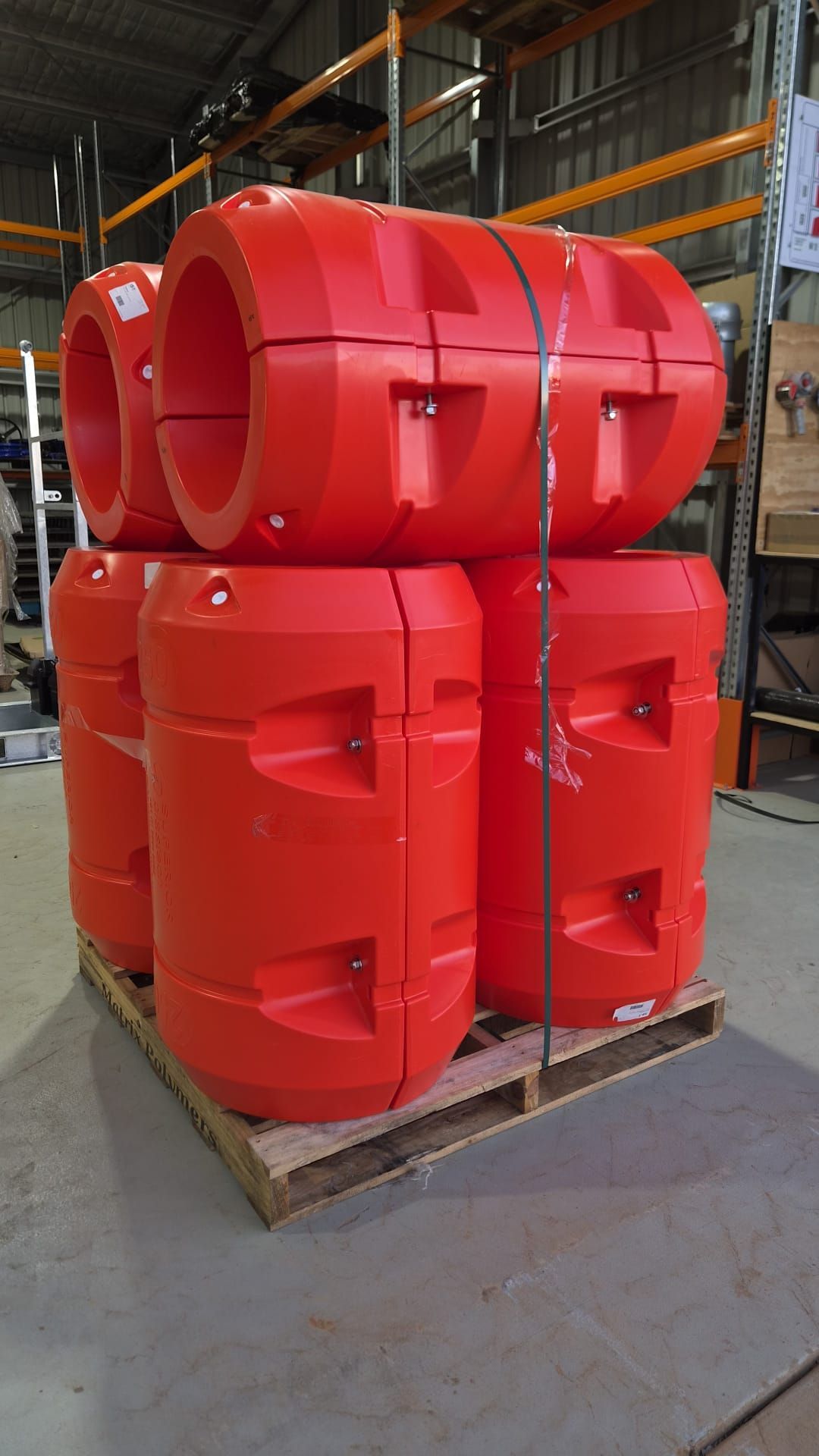 Stacked bright red industrial plastic tanks on a pallet in a warehouse aisle — Forcequip Hire In Moranbah, QLD