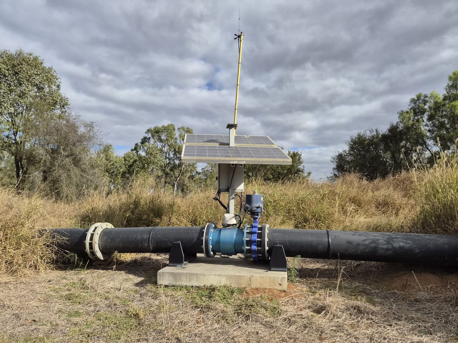 Solar-powered pipeline valve station in a grassy field under cloudy sky — Forcequip Hire In Mackay, QLD
