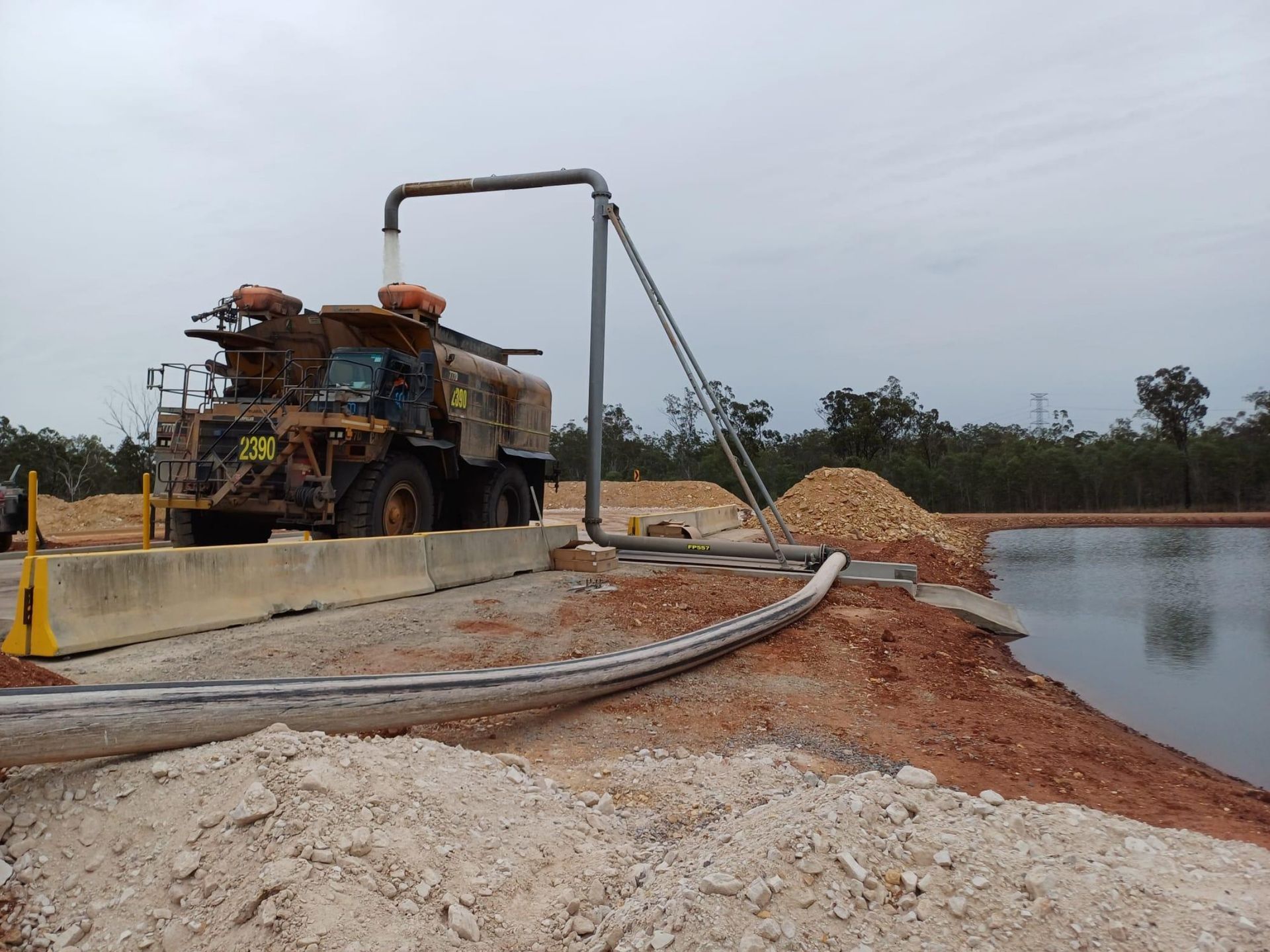 Truck Beside Water on a Dirt Embankment With a Pipe — Forcequip In Moranbah, QLD