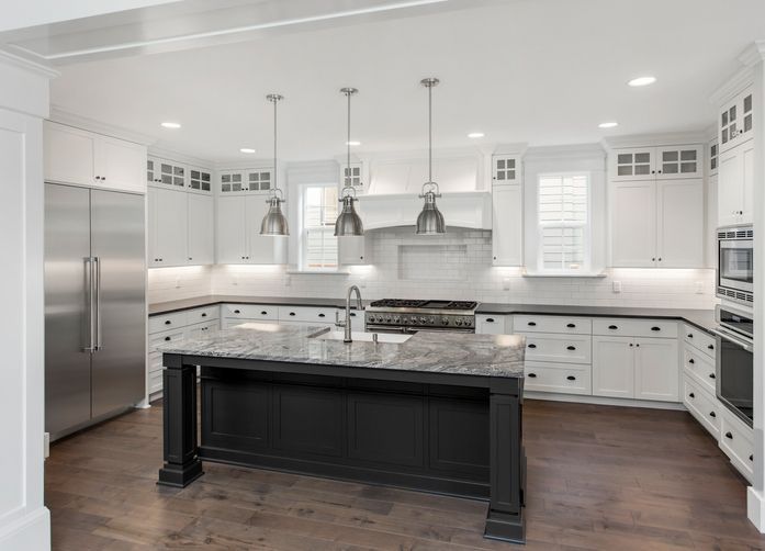 A kitchen with white cabinets , granite counter tops , stainless steel appliances and a large island.