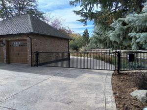 A brick garage with a wooden door is behind a metal gate.