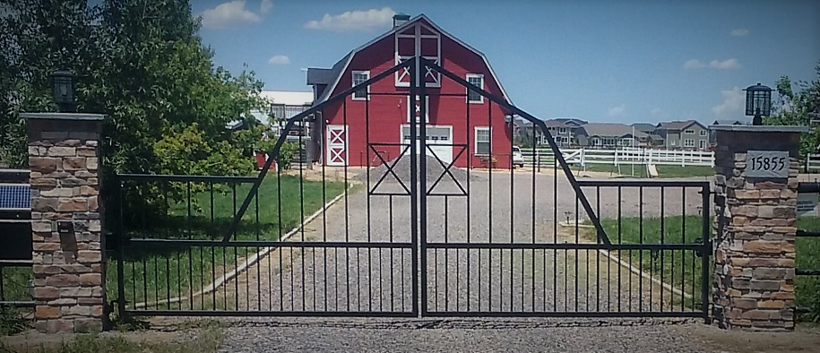 A red barn is behind a wrought iron gate