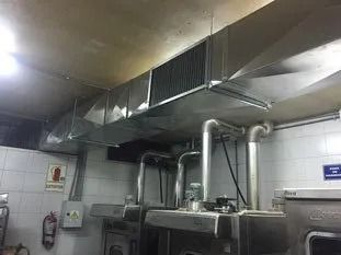 Techo de cocina comercial con conductos de ventilación de acero inoxidable sobre los equipos de cocción.