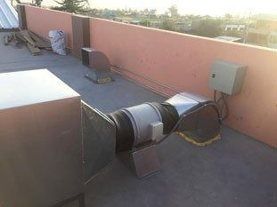 Conductos de climatización en la azotea con grandes tubos de ventilación redondos y una caja eléctrica