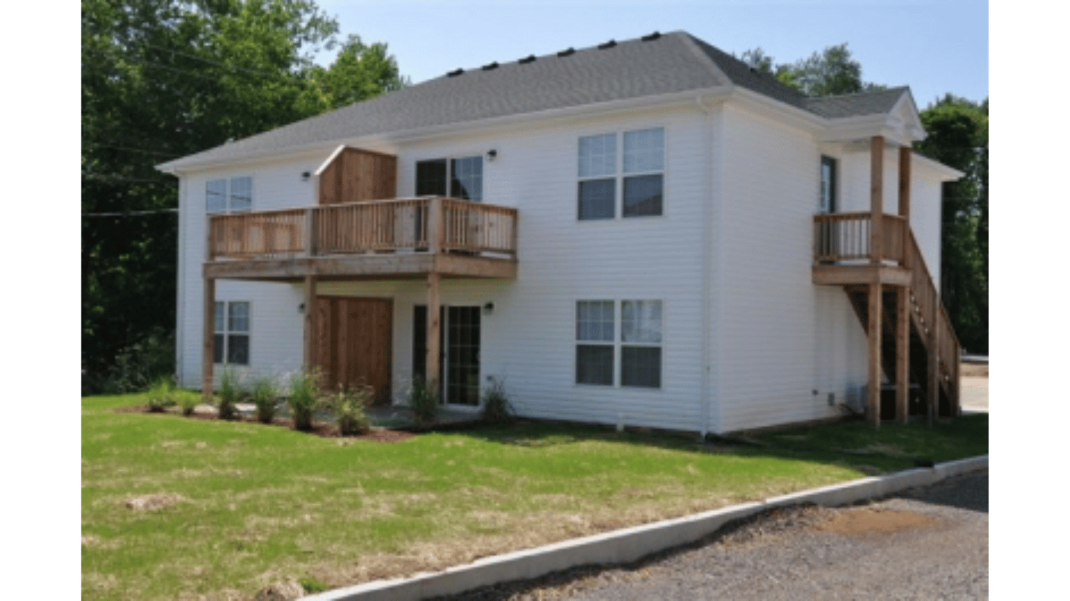 A white house with a wooden deck and stairs