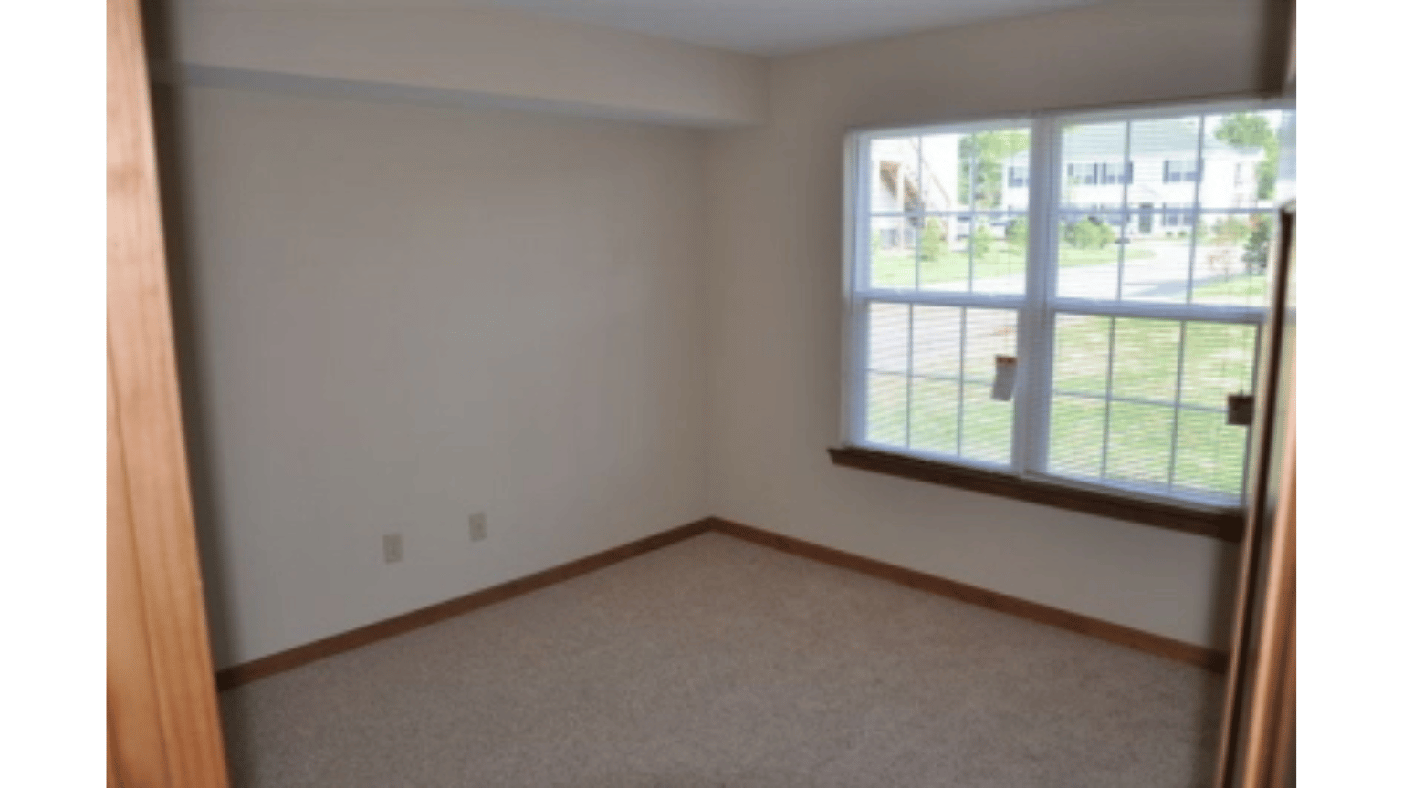 An empty room with two windows and a carpeted floor