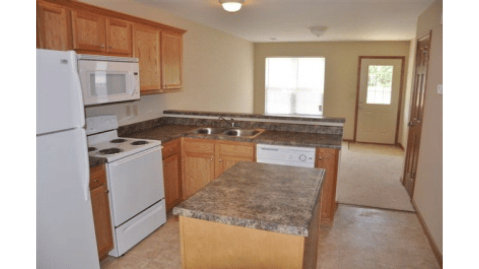 An empty kitchen with a refrigerator stove and microwave