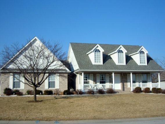 A house with a gray roof sits next to another house